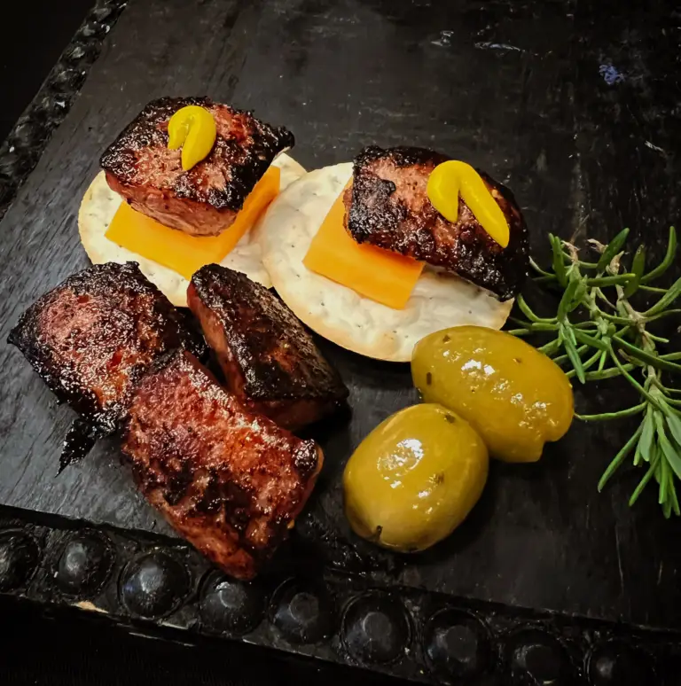 An appetizer of sausage, cheddar cheese, and olives
